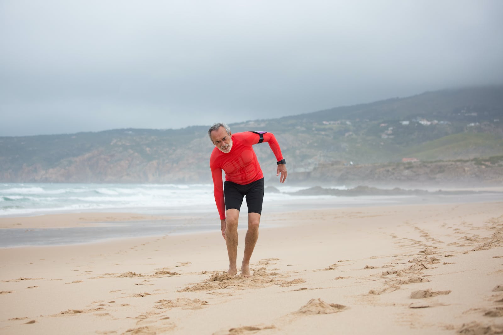 Man in Red Shirt and Black Shorts Feeling Pain in His Legs Chronic Pain With Exercise in Seniors