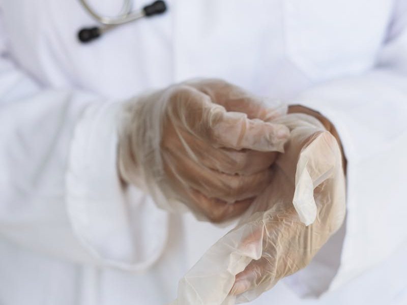 Faceless ethnic medical worker in lab coat and stethoscope taking of transparent gloves after approaching patients for examination in modern hospital Communicate Effectively With Health Care Professionals