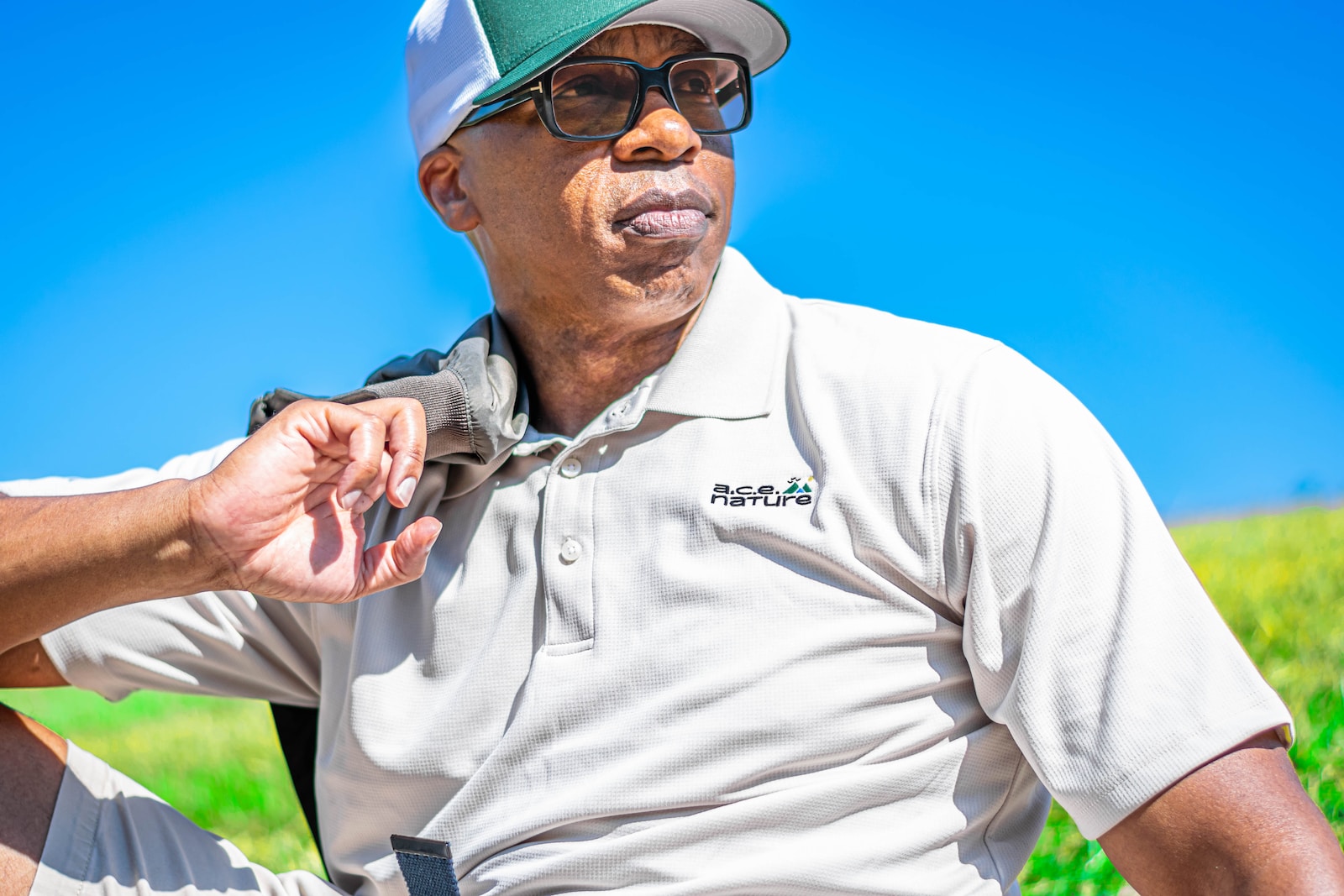 a man wearing a hat and glasses sitting in a field Golf for Seniors