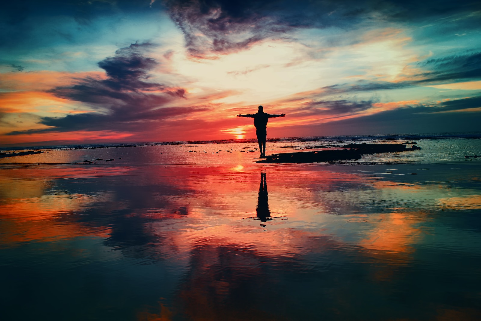 silhouette of person standing on rock surrounded by body of water Reiki and Energy Healing