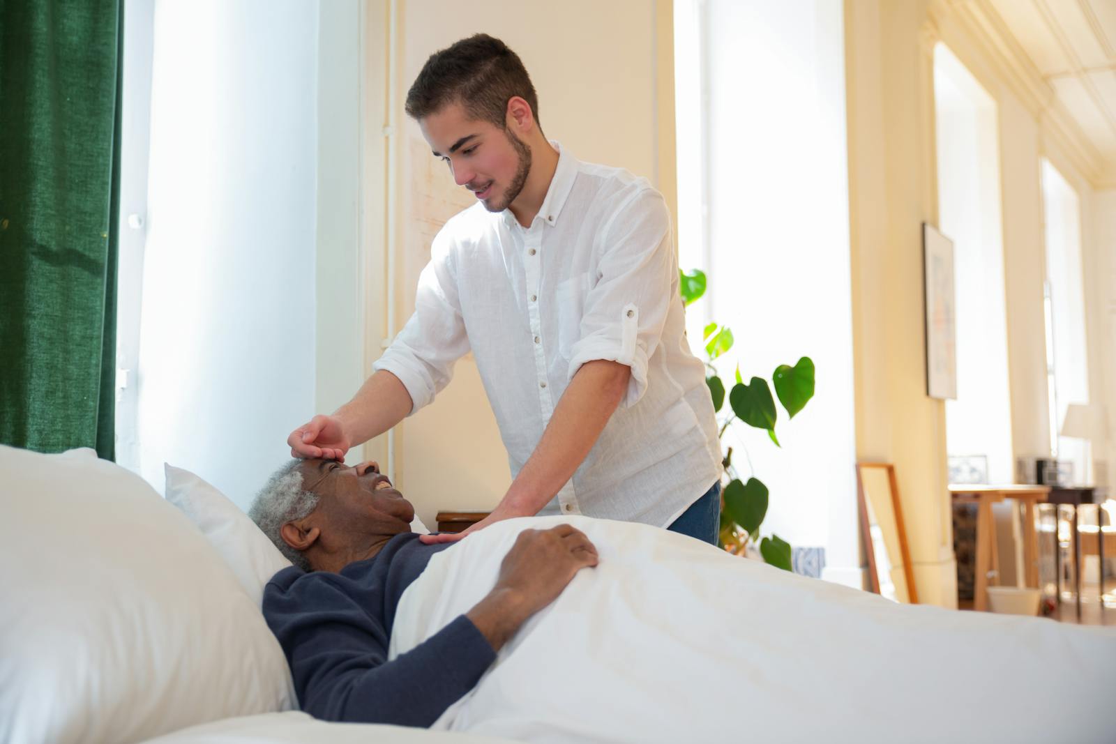 A Man in White Shirt Standing Beside an Elderly Lying on the Bed Resources for Caregivers